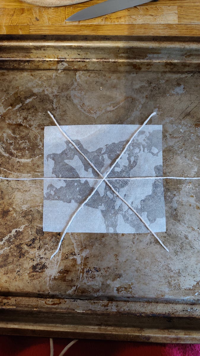 Prepare your equipment for shaping:
Cut 9 squares of greaseproof paper, lightly brush them with oil and spread them out on baking trays. Cut your string into 28 pieces (3 per donut), each around 18cm long. Oil the pieces of string and arrange 3 pieces of string on each greaseproof square so that they cross in the middle and form 6 segments, as shown.