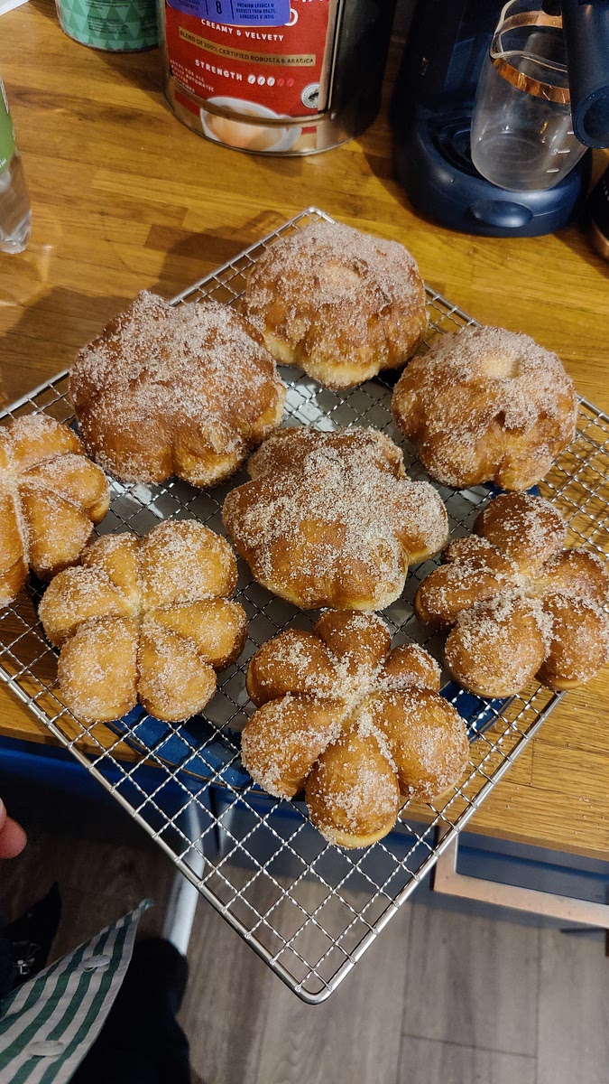 Once cooked on both sides, gently remove the donuts onto the cooling rack lined with kitchen towels to allow excess oil to be absorbed for a few seconds, then immediately toss in the spiced sugar mixture to coat the donuts.
Transfer to the second cooling rack and carefully snip the strings off.
