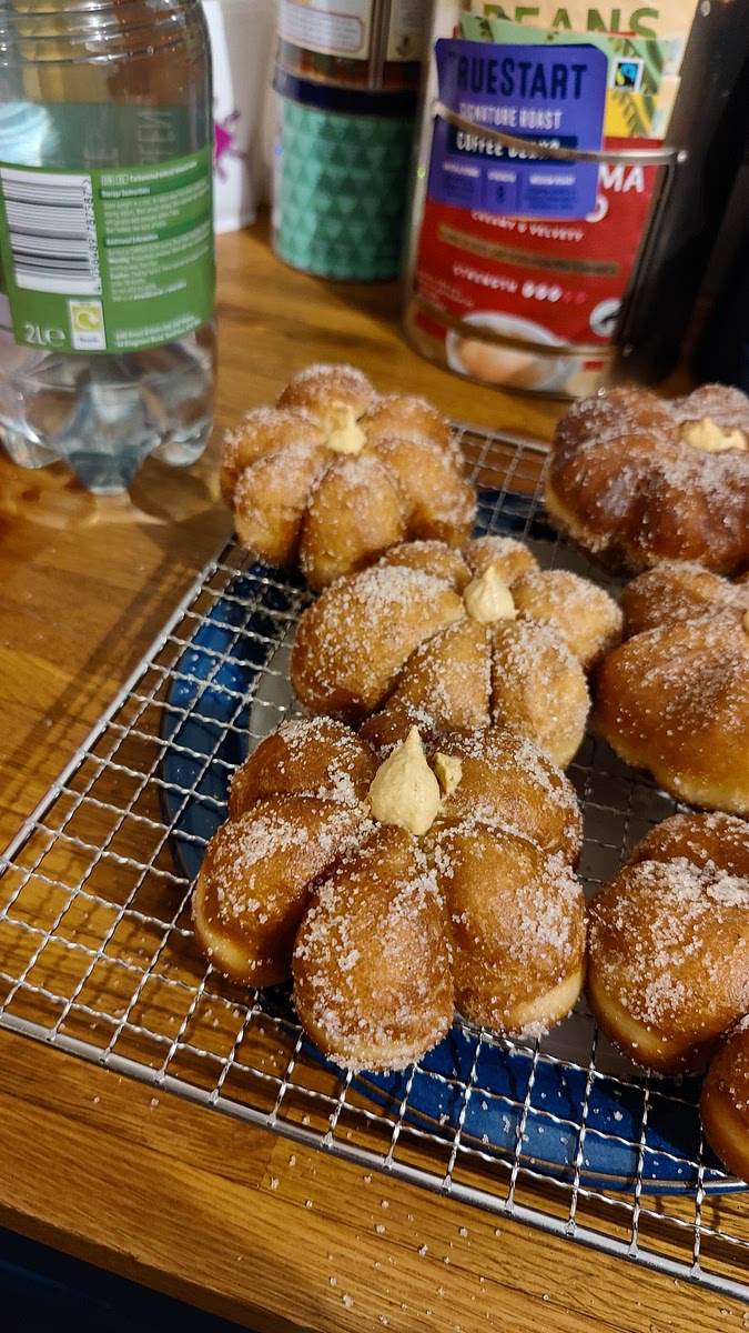 Holding the donut in one hand and the piping bag of filling in another, stick the nozzle of the piping bag right into the hole. Squeeze gently until you can feel the donut swell a little and the bag meets some resistance, then stop applying pressure and pull the piping bag out. Repeat for each donut.