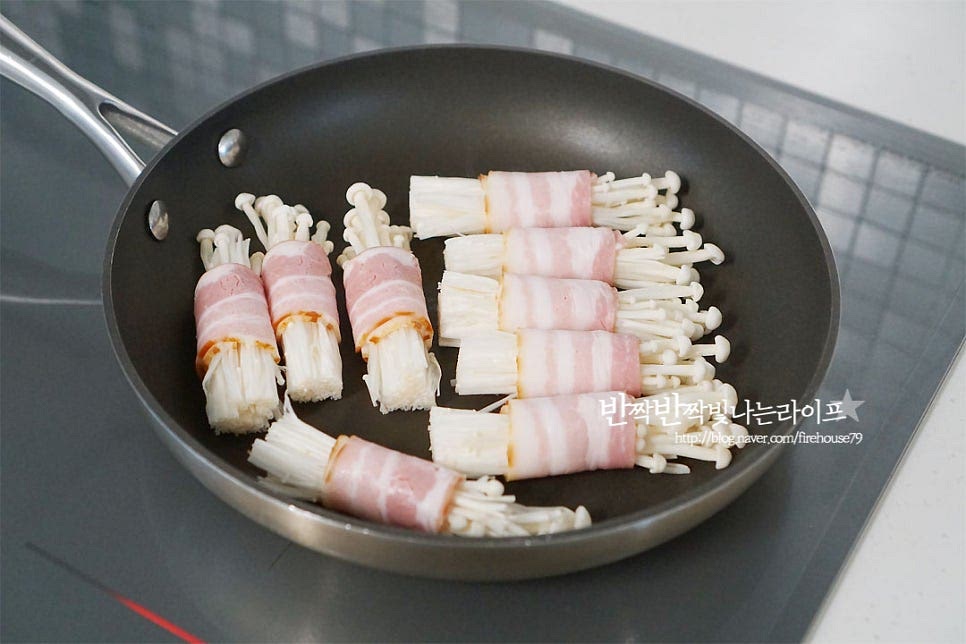 달군 팬에 올려 구워줍니다. 팽이버섯 베이컨말이 팁! 이음새 부분이 먼저 익을 수 있도록 바닥면을 향해 올려줍니다. 재료 자체에서 기름과 수분이 나와 따로 기름은 두르지 않으셔도 됩니다. 이음새 부분이 먼저 익어야 고정이 되어 풀리지 않고 모양을 잡아 만들 수 있어요. 돌려가며 노릇노릇하게 구워줍니다. 따로 소금 간은 하지 않고 후추 약간 뿌려주었어요. 간은 기호에 맞게 해주세요~ 뜨거울 때 먹어야 식감 그대로 맛있게 즐길 수 있죠. 그릇에 먹기 좋게 담아내면 초간단 팽이버섯요리 뚝딱입니다. 영상도 같이 담았어요. 돌돌 말린 고소한 감칠맛에 쫄깃쫄깃 씹히는 식감이 어우러져 맛궁합이 아주 좋아요. 맥주한잔이 절로 생각나는 맛이죠. 베이컨팽이버섯말이 맛있게 만들어 드세요^^ 끄읕 !