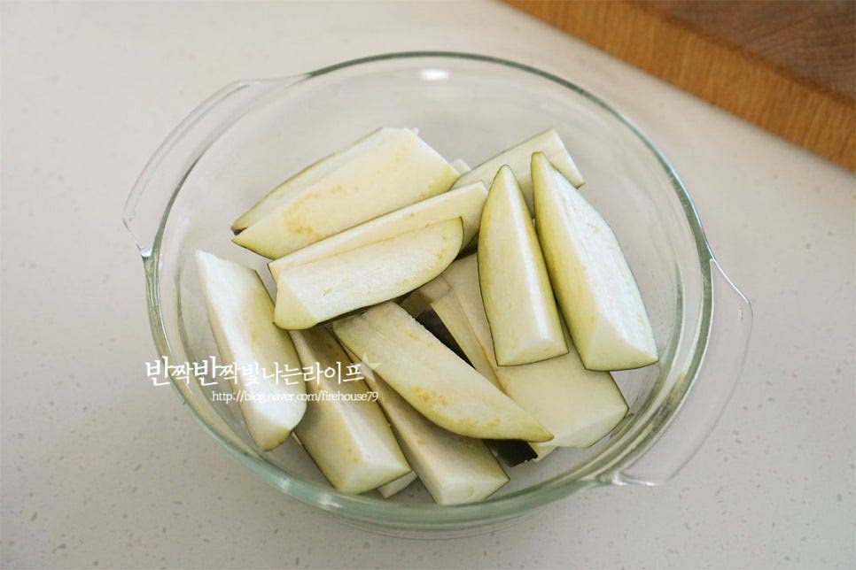 찜기를 활용해 보드랍게 쪄도 되지만 불을 사용하지 않고 전자렌지로 간단하게 만듭니다. 전용 용기에 가지를 담아줍니다. 수분이 많기 때문에 물을 따로 넣을 필요 없이 전자레인지에 넣어줍니다. 가지 찌는 시간은 2개 기준 3분~3분 30초로 양이나 기기의 사양에 따라 시간을 조절해 주세요. 3분 정도를 기준으로 상태를 보고 시간을 조절해 주면 됩니다. 뚜껑을 열어보니 부드럽게 잘 익었어요. 크기에 따라 큰 경우 먹기좋게 찢어줍니다. 한 김 식힌 뒤 물기를 짜줍니다. 속이 부드럽기 때문에 가지나물무침이 물러지지 않게 지그시 힘을 주고 짜줍니다.