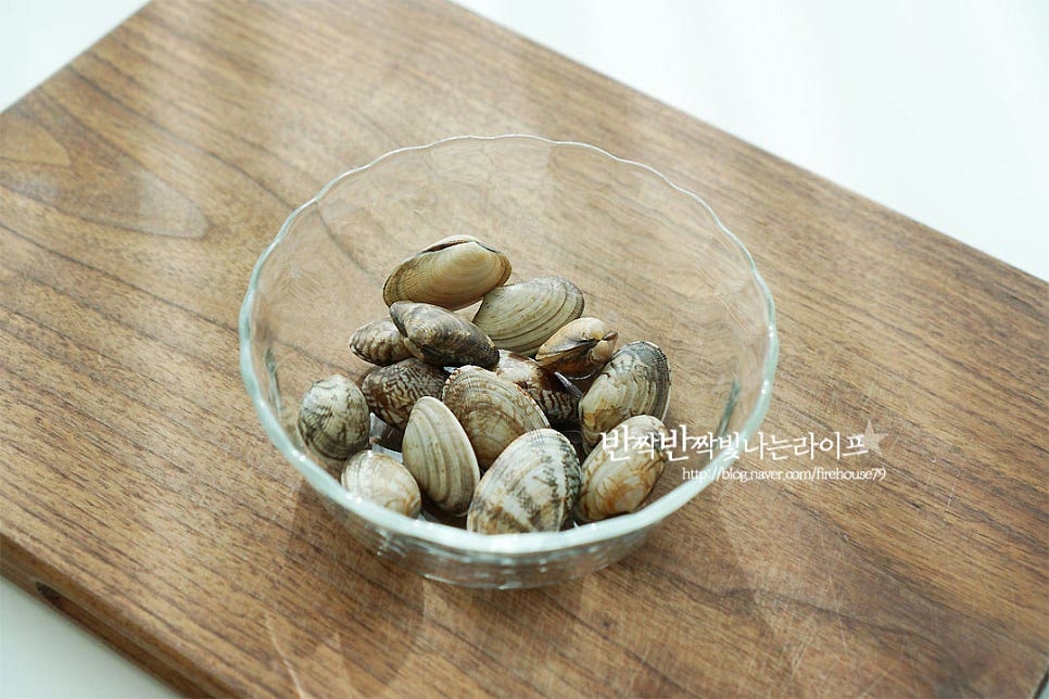 연어가 주재료이지만 같은 바다에 사는 해산물을 곁들이면 더 감칠맛이 좋은데요. 조개, 새우와 같은 재료를 준비해요. 소금물에 해감 손질한 바지락을 준비했어요. 양파는 굵게 슬라이스하여 줍니다. 방울토마토는 꼭지를 제거하고, 양송이버섯은 밑동 끝부분을 손질하고, 아스파라거스는 줄기 질긴 부분을 감자칼로 제거해 줍니다. 레몬과 마늘은 슬라이스해주어요.