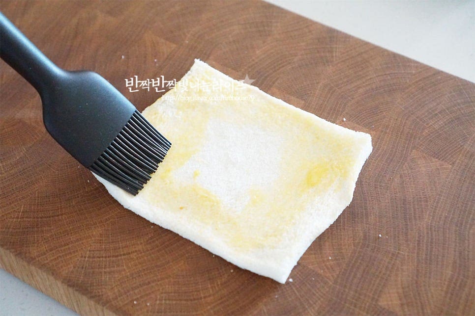 식빵 모서리 끝부분에 계란물을 발라줍니다. 그대로 말아주는 것보다 달걀물을 바르면 빵이 고정되어 길쭉한 핫도그가 만들어집니다. 전처리한 소시지에 슬라이스치즈를 돌돌 말아줍니다. 소세지만 넣어도 탱글하고 짭조름하지만 치즈를 함께 넣으면 고소하게 늘어나는 맛이 별미에요. 소시지를 반으로 자르고 모차렐라 스트링치즈를 넣어 반반 치즈핫도그를 만들어도 좋고요. 계란물 바른 빵 위에 올려 돌돌 말아줍니다. 끝부분이 풀어지지 않도록 고정해 줍니다. 양 끝도 꼼꼼하게 오므려 고정해요.