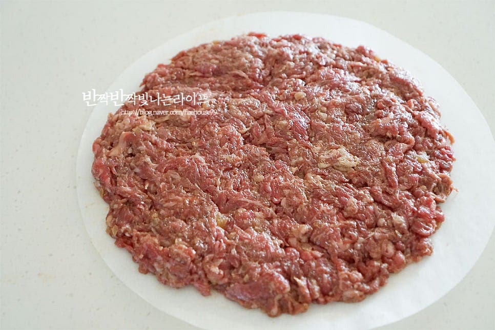 프라이팬 크기의 종이호일을 준비한 뒤 양념한 소고기를 넓게 펼쳐 올려줍니다. 너무 얇거나 두껍지 않게 만들면 촉촉하고 식감도 느껴집니다. 류수영 레시피는 한 번에 250g 정도씩 만드는데 저는 조금 크게 300g 2개로 만들었어요. 구워지면서 수축되기 때문에 그 부분을 참고하여 크기를 잡아주세요.