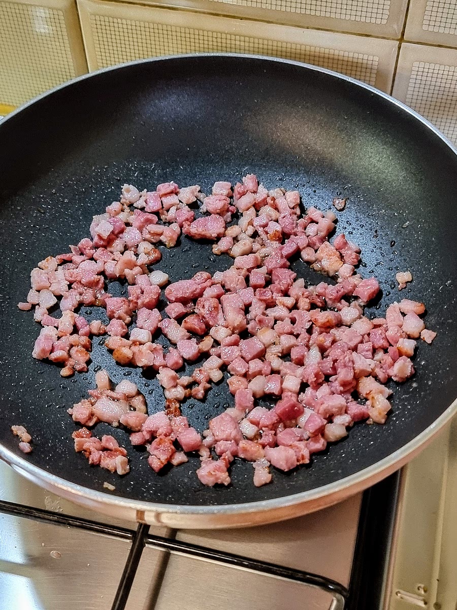 Nel frattempo, versare il guanciale a cubetti in una padella alta e capiente (saltapasta) calda, senza aggiungere olio. Lasciare rosolare a fuoco medio/basso a piacere (più tempo si lascia, più il guanciale diventa croccante e sapido).