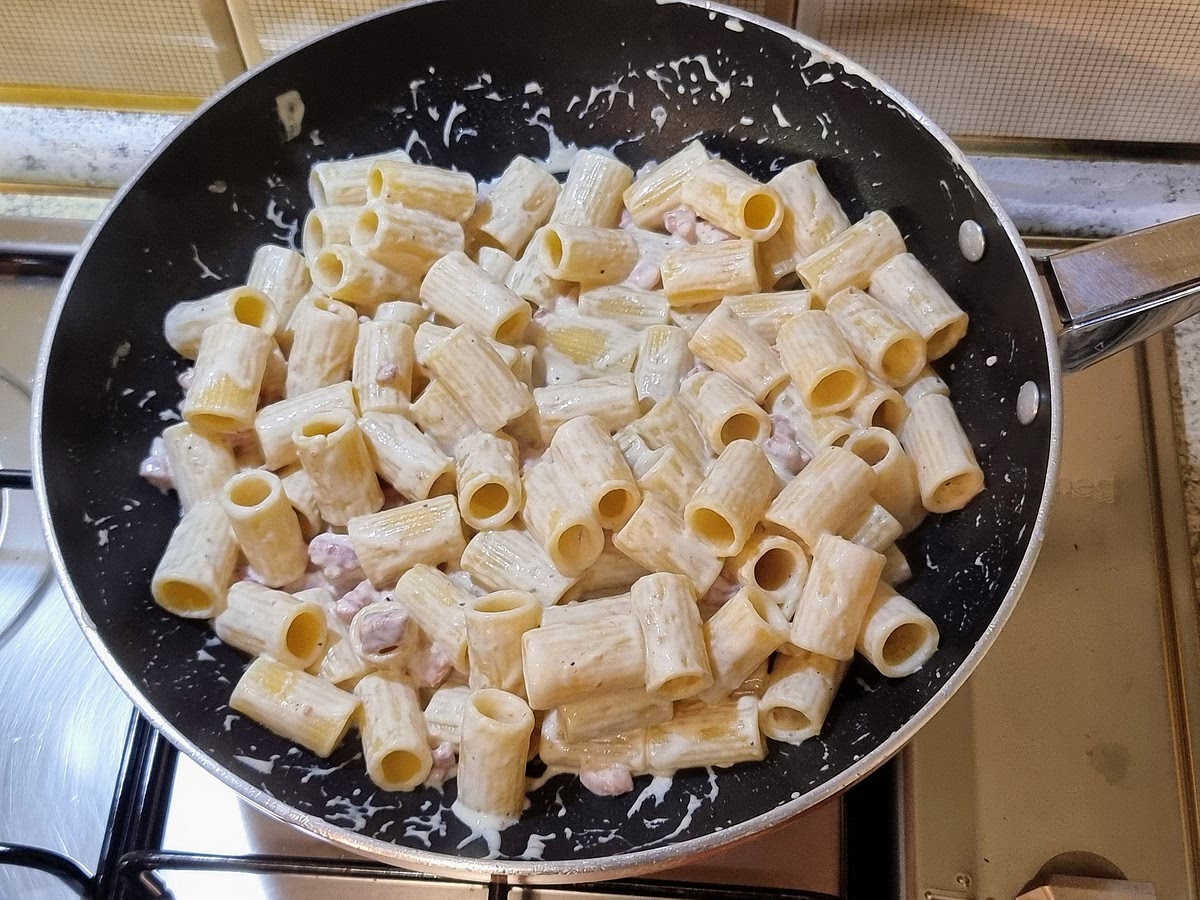 Mescolare la pasta, la crema e il guanciale nella padella a fuoco vivace per alcune decine di secondi. Se la crema si rapprende troppo, aggiungere acqua di cottura della pasta poco alla volta - quanto basta per mantenere il tutto cremoso, senza annacquare.
