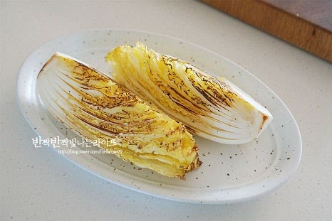 접시에 샐러드를 담아줍니다. 두 조각을 먹기 좋게 담은 뒤 그 위로 베이컨과 마늘을 올려줍니다. 파마산 치즈를 갈아서 올려줍니다. 치즈를 듬뿍 갈아주고 올리브오일만 뿌려서 마무리해 달큰하고 고소한 맛 그대로 즐겨도 맛있어요. 입맛에 따라 쪽파나 크러쉬드 레드페퍼를 뿌려 마무리 완성합니다.