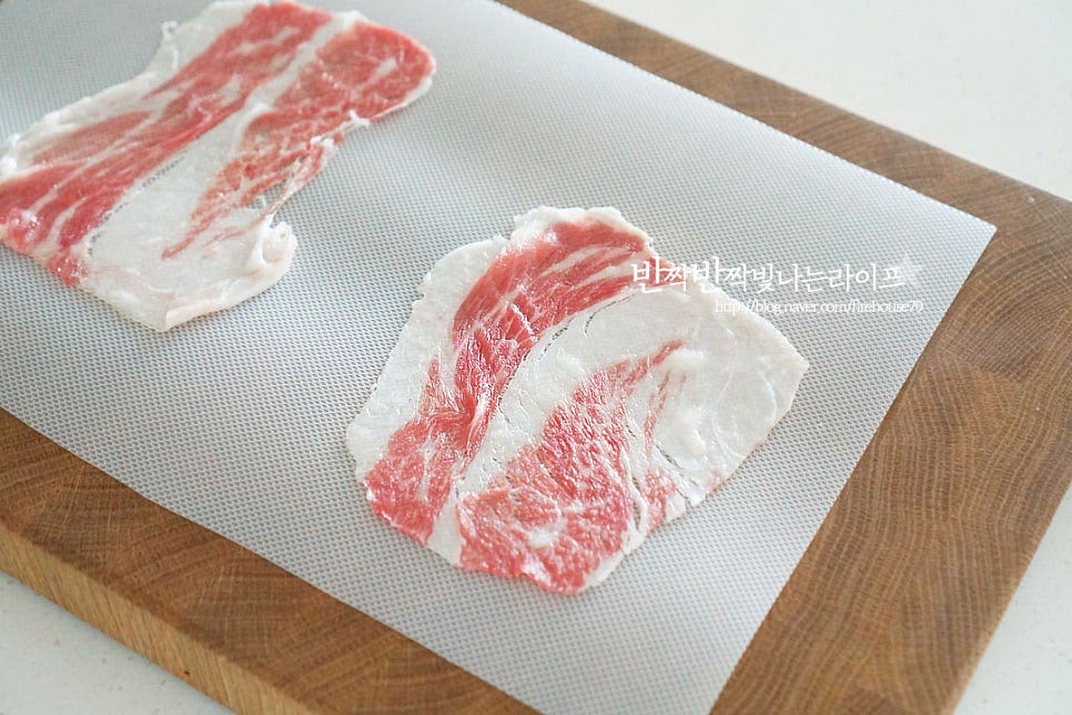 소고기를 넓게 펼쳐줍니다. 그 위로 깻잎을 올리고 부추와 팽이버섯을 조금 덜어 올려줍니다. 한입에 먹기 좋은 크기로 말아주는데요. 익으면서 수축되기 때문에 그 부분을 생각하여 모양내어 주세요. 끝부분에 찹쌀가루 약간 발라서 고정하여 주면 모양이 더 잘 잡힙니다. 이 과정을 반복하여 말아줍니다.