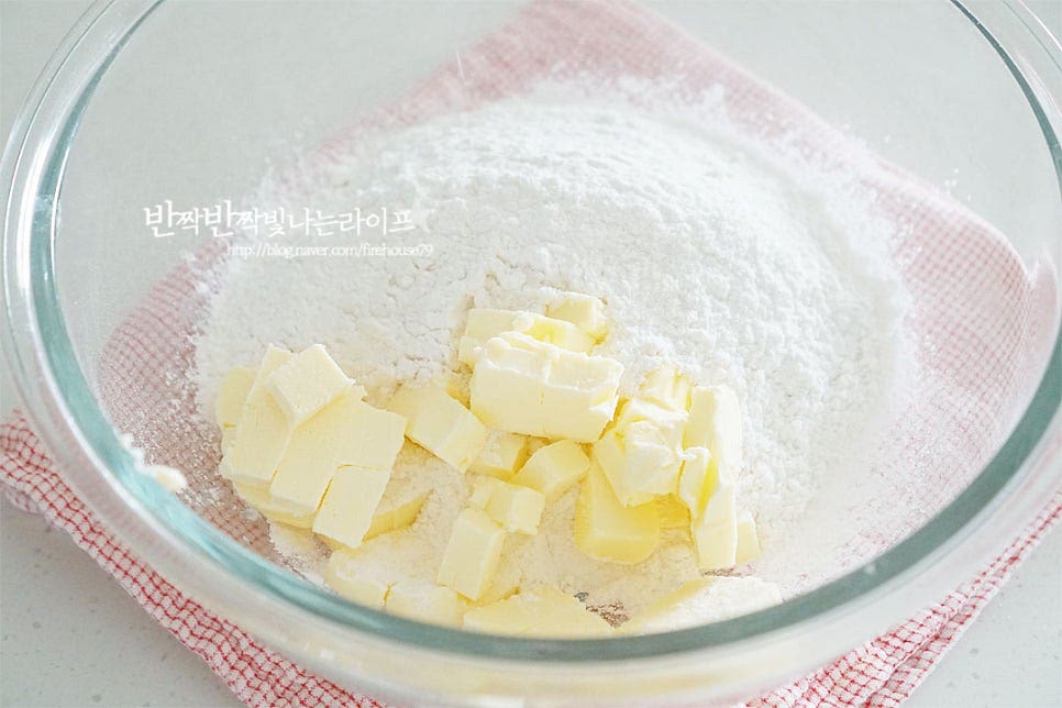 곱게 내린 가루에 차가운 버터를 넣고 섞어주는데요. 이때 반죽으로 뭉치는 것이 아닌 스크래퍼 또는 푸드프로세서로 버터를 잘게 자른다는 느낌으로 섞어주세요. 손의 온기로 녹지 않도록 도구를 활용합니다. 스크래퍼를 세워가며 잘라줍니다. 차가운 상태로 녹지 않게 빠르게 섞어주고 자르듯이 움직이다 보면 작은 쌀알 크기로 섞입니다.