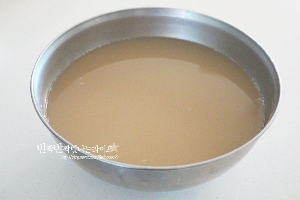 대략 1시간 가까이 두었더니 앙금이 가라앉고 윗부분이 맑아졌습니다. 고두밥이 지어지면 고슬고슬하게 가볍게 저어 섞어줍니다. 가라앉힌 앙금이 섞이지 않게 윗부분의 맑은 물을 부어줍니다. 아랫부분에 보면 하얀 앙금이 가라앉아있어요. 설탕 100g도 함께 부어줍니다. 설탕이 조금 먼저 들어가면 삭히는 데 도움이 됩니다. 가볍게 섞은 뒤 전기밥솥에 넣어줍니다. 보온으로 설정한 뒤 따뜻한 온도를 유지하여 삭혀줍니다. 대략 5~7시간 정도 그대로 보온을 설정해둡니다. 거의 6시간 가까이 되어서 뚜껑을 열어보니 밥알 몇 개가 동동 떠있습니다. 그럼 잘 삭혀진 것이랍니다.