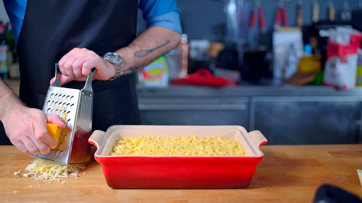 Transfer the pasta mixture to your casserole dish, smooth it all out to form an even layer, then cover with shredded yellow and white cheddar cheese along with the grated parmesan