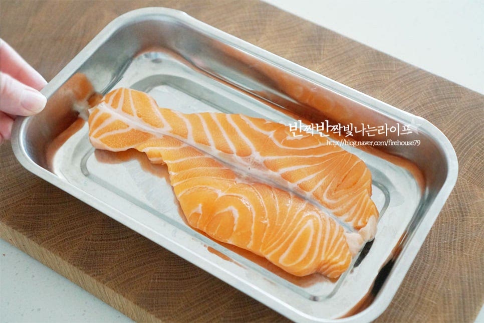 스테이크용 연어로 구이로 요리하기 좋은 몸통 부분을 두툼하게 자른 것을 준비했어요. 타월로 겉의 수분을 꼼꼼하게 제거하여 비린내없이 깔끔하게 손질해 줍니다. 육류로 스테이크를 만드는 것과 같이 고소한 풍미를 끌어올려 굽기 위해 밑간해줍니다. 화이트와인 1 큰 술을 골고루 뿌려줍니다. 소금, 후추 약간을 뿌리고 올리브오일를 골고루 바르고 허브(타임)를 곁들여 시즈닝해줍니다. 재료에 기름이 많이 나오기 때문에 풍미를 살려줄 정도의 올리브오일에 밑간해줍니다.