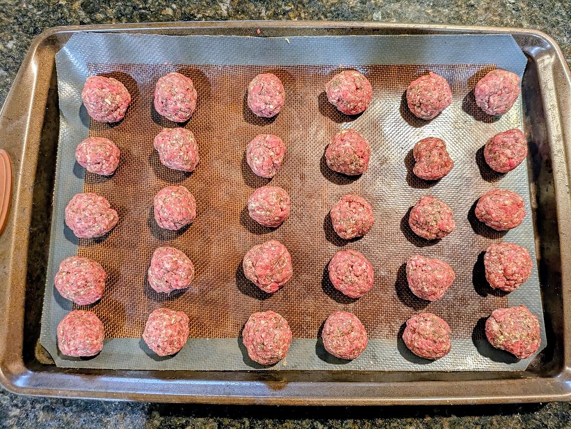 Scoop your meat mix into 30 meatballs, about 24 g each. Roll into a ball, and place on the other cookie sheet