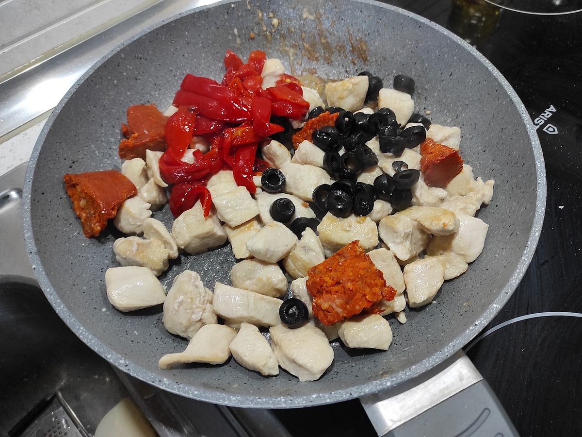 Agregar los trozos de sobrasada, dejar fundir y mezclar. Luego agregar los pimientos y las aceitunas.
Deglasar con vino blanco para recoger el fondo, dejar evaporar el alcohol.