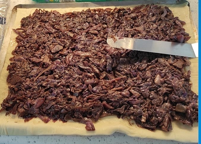 Extender la masa 30x40cm y colocarla sobre una asadera forrada con papel de horno. Dejando un borde alrededor de 1cm, disponer el relleno de lombarda/cebolla uniformemente con una espátula. Distribuir encima las fetas de provolone (opcionalmente,. mozzarella rallada).