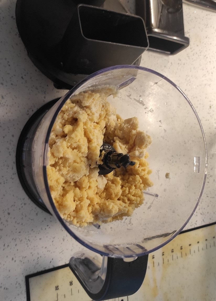 Al granulado, agregar el huevo y luego el agua hasta lograr que se "apelotone", pasarla a la encimera y amasar hasta incorporar y alisar. Aplanar en forma de círculo, envolver con película y reposar en frigo por una hora.