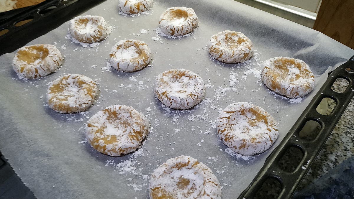 Sobre una asadera recubierta de papel horno, disponer cada bola, aplanar y crear un hueco más o menos profundo. Dejar espacio suficiente entre cada galleta (aunque no se expanden dueante la cocción, es importante que circule el aire entre ellas).