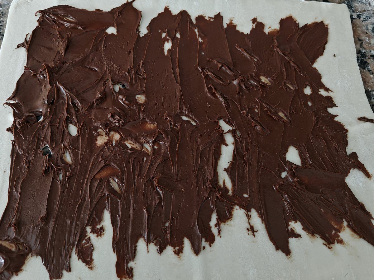 Extender la masa de hojaldre y untar una fina capa de crema de chocolate.