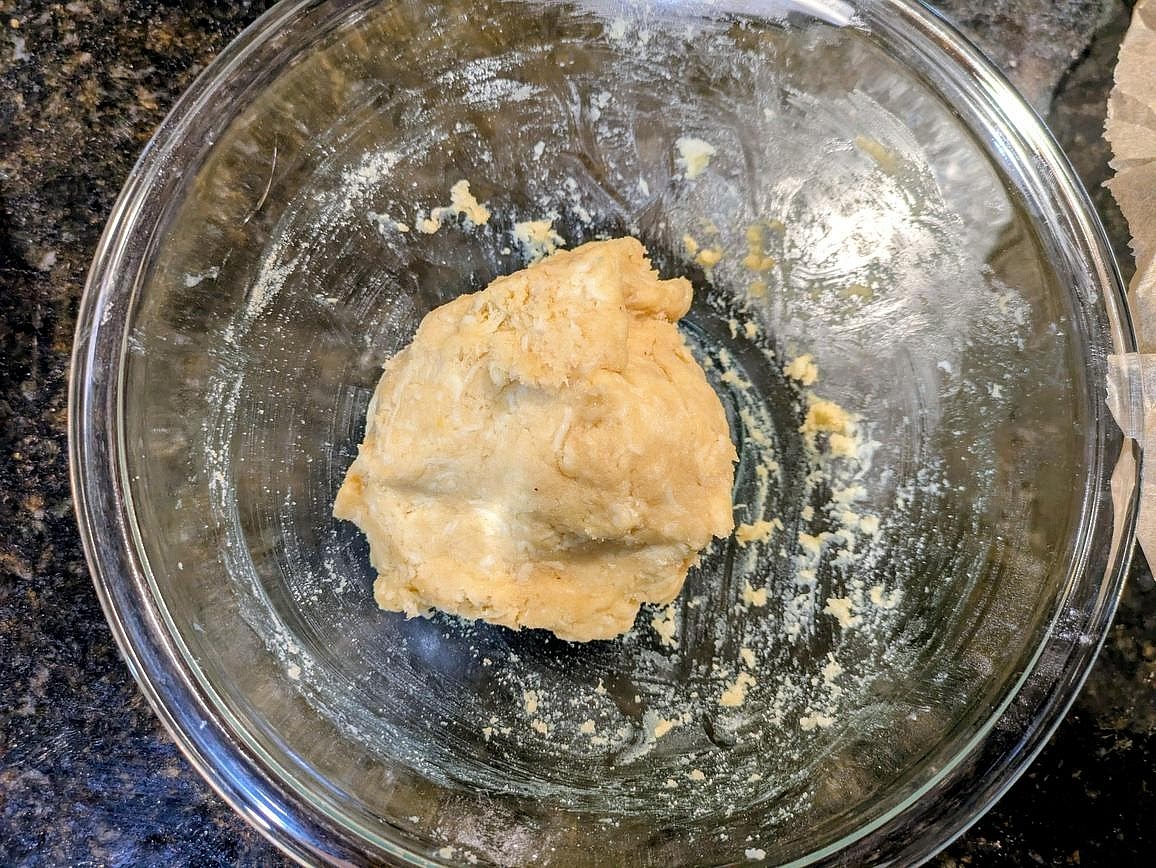Mix in the almond flour and baking powder with a silicone spatula. Add in a beaten egg, and combine with the spatula. Switch to your hands, and knead until fully combined. The dough should be slightly sticky