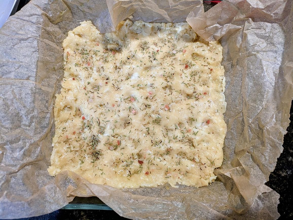 Press the dough to the baking dish. Make dimples in the dough with your fingers. Top with rosemary and salt, and lightly press them into the dough. Optionally spray the top with olive oil