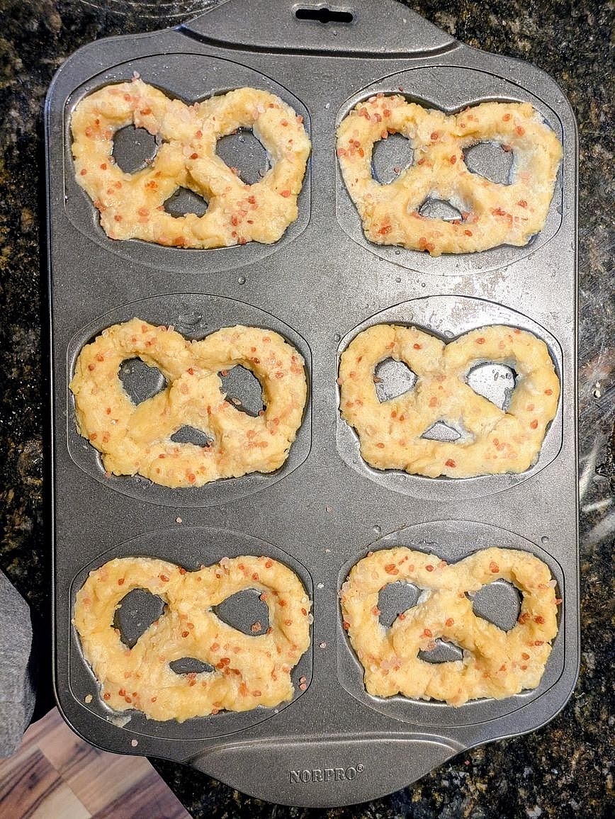 Divide into 6 equal pieces (about 70 g each), and shape into pretzels on your prepared pan. Brush the tops with water. Sprinkle the tops with flaky salt or everything bagel seasoning