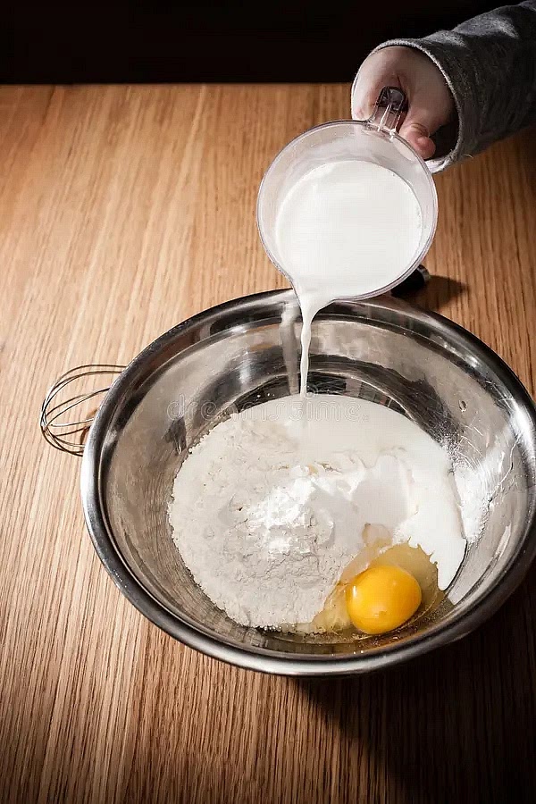 Quand le mélange devient épais et difficile à tourner, versez le lait froid petit à petit, toujours en fouettant énergiquement.