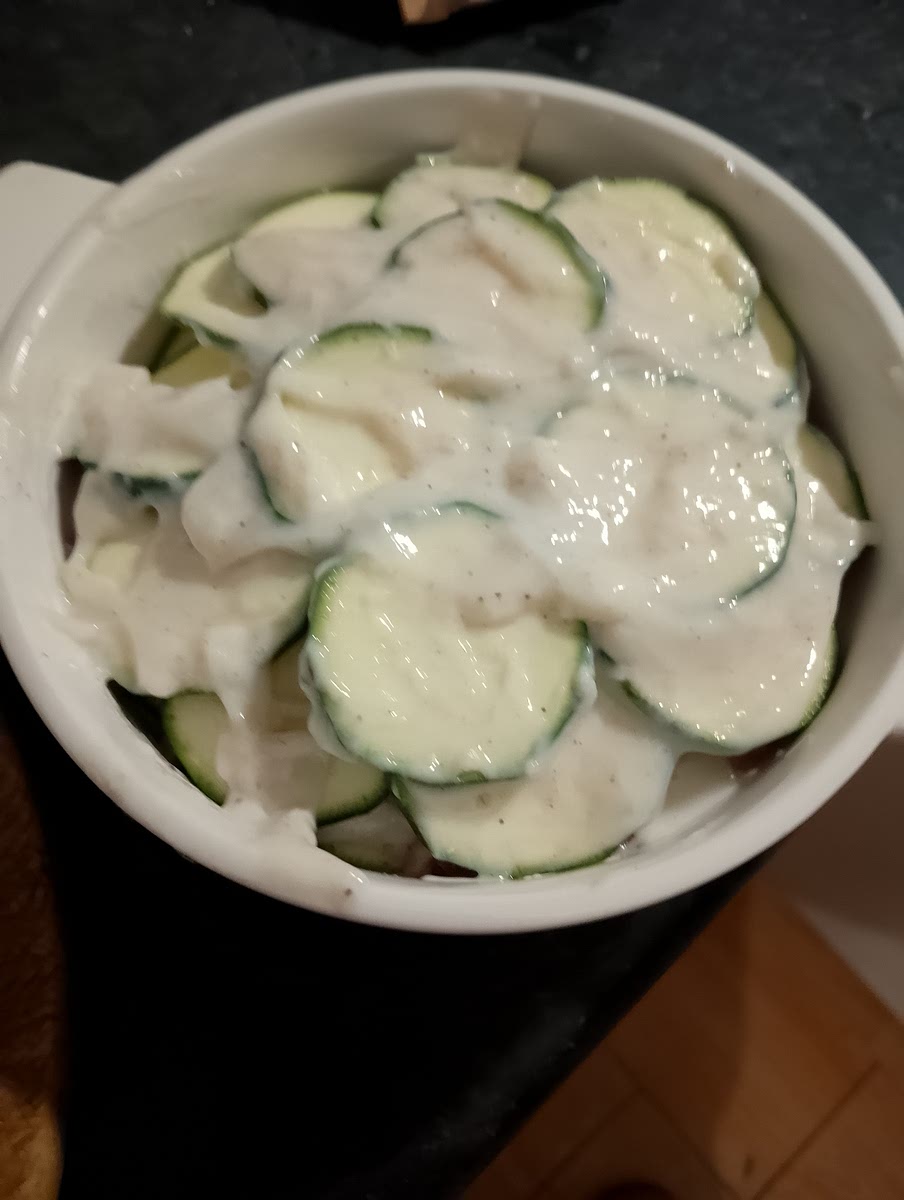 Ajouter par-dessus la moitié des allumettes de bacon puis recouvrir d'un peu de béchamel.
Remettre une couche de courgettes en rosace, le reste des allumettes de bacon et une couche de béchamel et finir par une dernière couche avec les dernières rondelles de courgettes et le reste de béchamel.