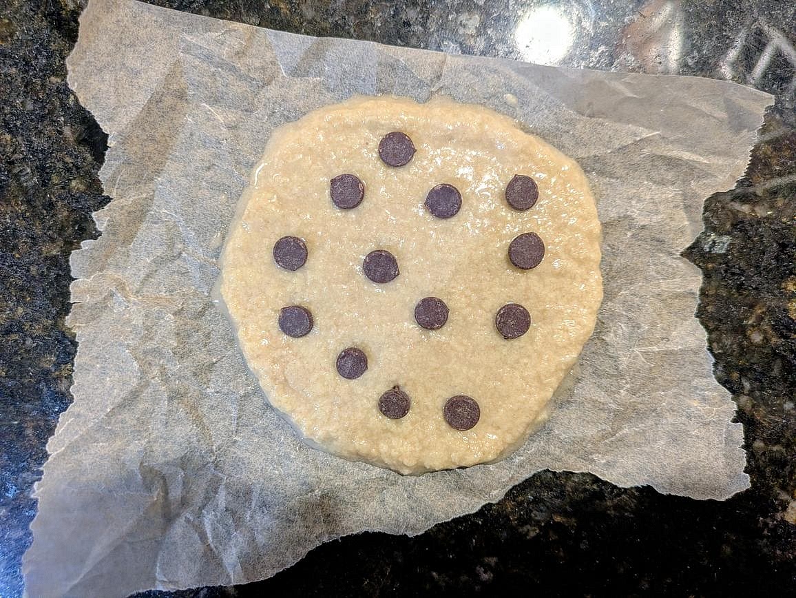 Transfer your cookie dough to a small piece of parchment paper. Flatten to a 1/4" circle. Press the chocolate chips into the top