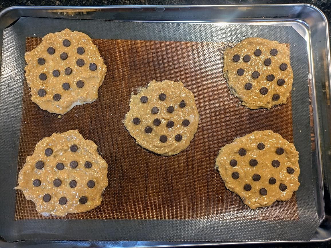 Use a spoon to scoop the batter onto the pan, about 60 g each. Lightly wet the back of a spoon, and flatten to a 1/4" thick circle. Press the chocolate chips into the top, about 1 tsp (6 g) per cookie