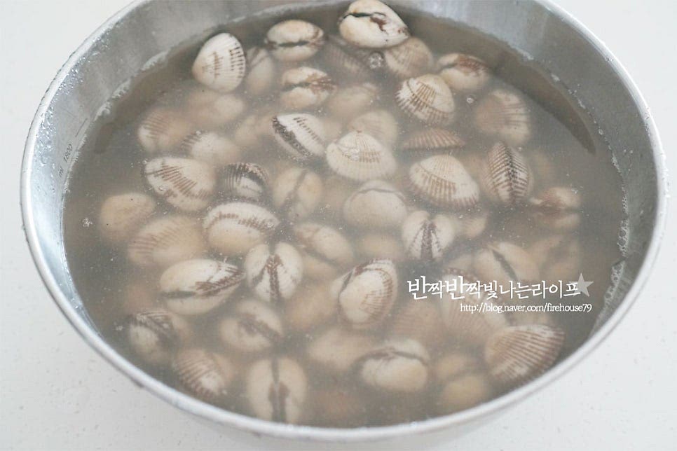 꼬막은 800g 정도를 준비했습니다. 뻘에서 나는 식재료라 생각보다 불순물이 꽤 많이 나오는 편이라 손질을 꼼꼼하게 해줍니다. 넉넉한 크기의 볼에 물과 담은 후 서너 번 정도 껍데기를 흔들어 세척해 줍니다. 너무 힘을 세게 주면 껍질이 깨질 수 있은 살짝 흔들어가며 씻어줍니다. 세척 후 해감을 하기 위해서 스테인리스 냄비 또는 볼에 꼬막이 잠길 정도로 물을 붓고 소금 1 큰 술을 넣고 녹인 다음 뚜껑을 덮거나 검은 비닐을 씌워 빛이 들어가지 않도록 차단하고 어둡고 서늘한 곳에서 1시간 정도 이상 해감해 줍니다. 날씨에 따라 냉장고에 넣어서 해감해 주고 스테인리스 소재를 사용하면 해감에 도움이 되며 저와 같이 냄비와 뚜껑을 활용하면 간편합니다. 1시간 이상 두었다가 열어보면 꼬막이 이물질을 뱉어내고 물이 뿌옇게 되어있습니다. 조개는 흐르는 물로 바락바락 문질러 깨끗한 물이 나올 정도로 세척한 뒤 채반에 밭쳐 물기를 털어줍니다.