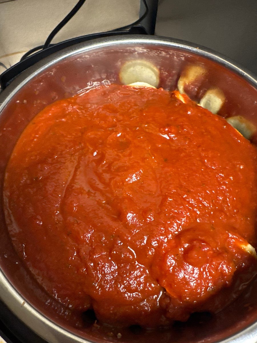 Pour the entire jar (24oz) of spaghetti sauce over the ravioli. Spread it to cover the pasta, but DO NOT STIR. This layering keeps the thick sauce off the bottom and prevents the burn error.