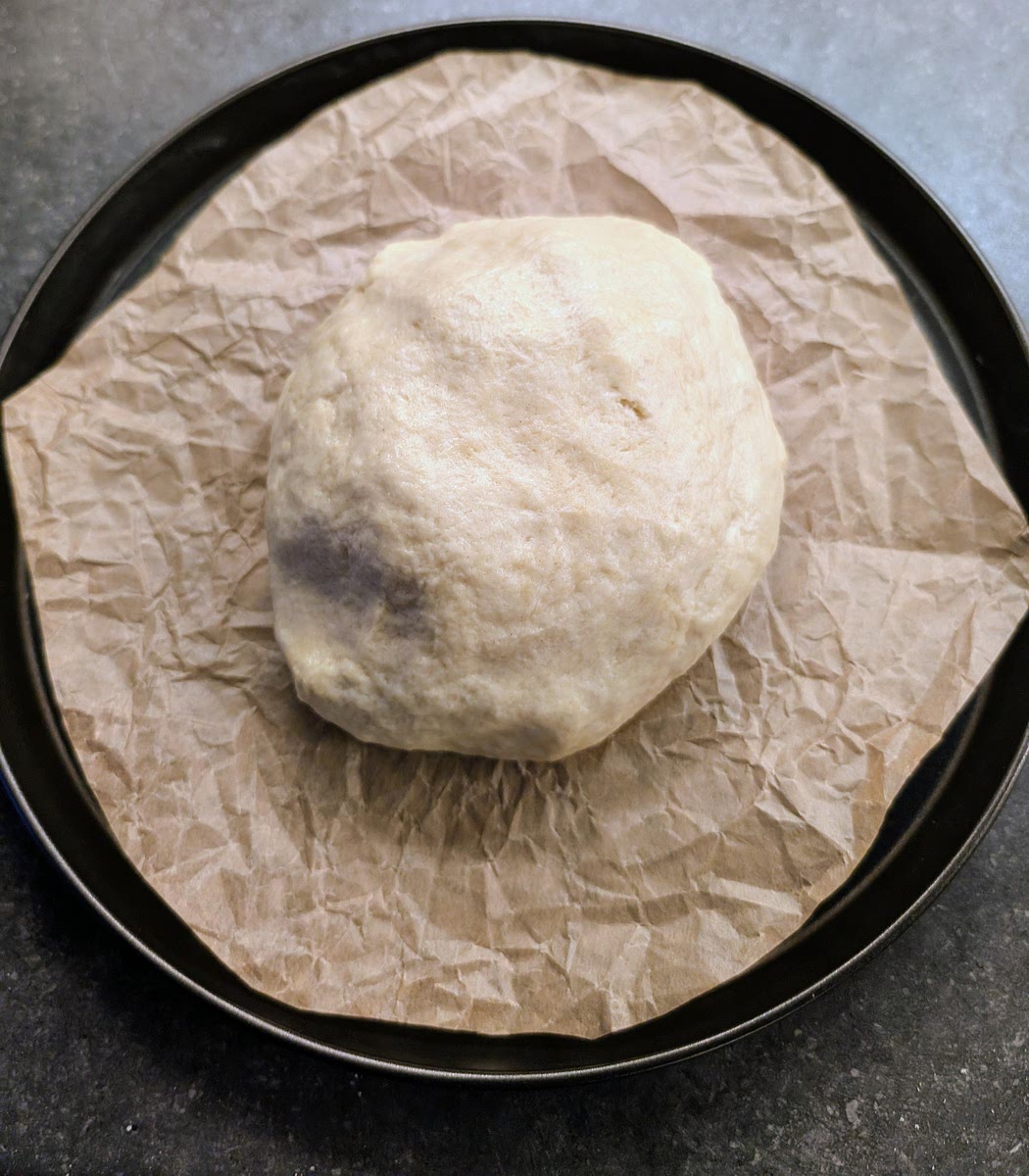 Line a 28cm steel pizza pan with parchment paper and ojace the ball of dough in the middle