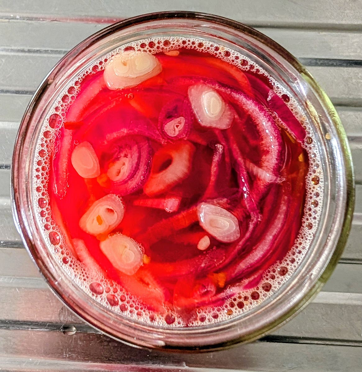 Let it cool down to room temperature. As it cools, the onions will pick up the flavour from the liquid, while colouring it. The colour will even up on the onion slices, becoming bright pink throughout.