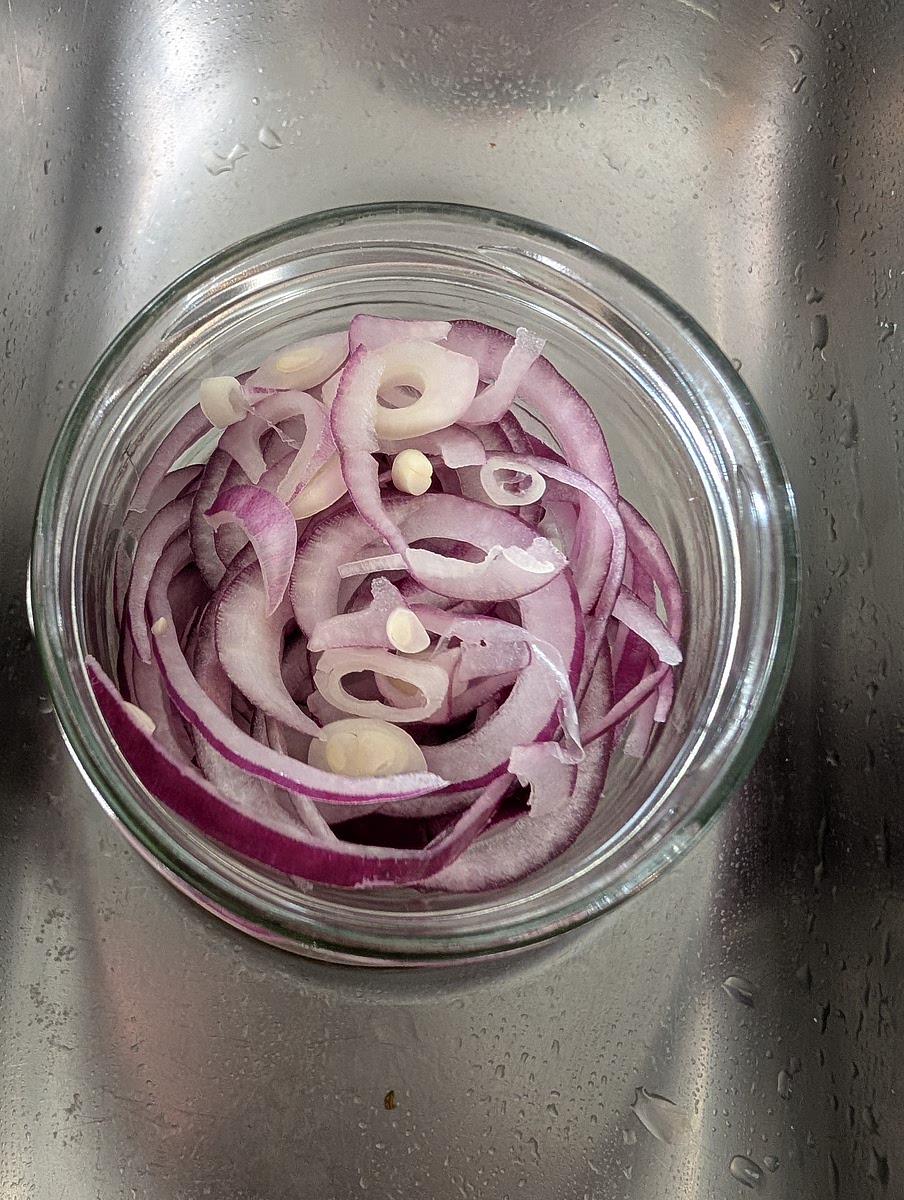 Place the rsliced onion in a mason jar (or jam jar) and place the jar in the sink to catch any spillage.