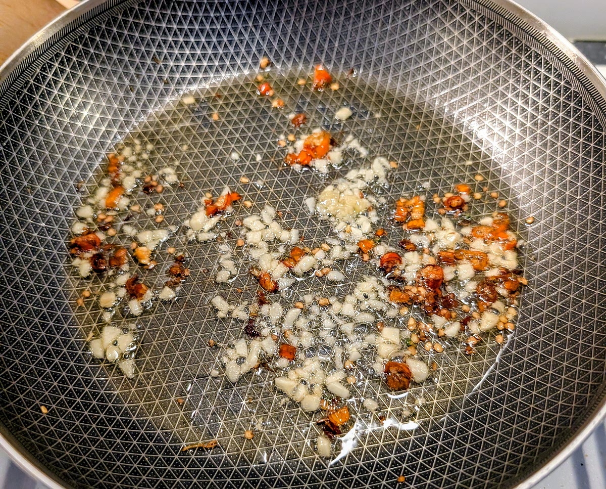 While the pasta is cooking, heat 2 tbsp of olive oil in the frying pan to medium heat, add the chillies, garlic and a pinch of sea salt, and fry them at medium heat for 1 minute.