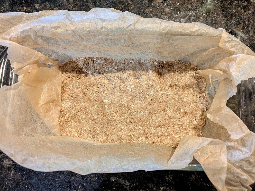 Line a 9x5" bread pan with parchment paper. Lightly wet your hands to prevent sticking, and evenly press the crust into the pan