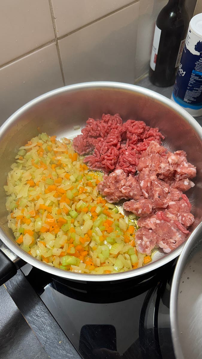 Ajouter le hachis de bœuf et la chair des saucisses directement avec le mirepoix. Saler et poivrer.
Cuire sur feu à ~7/10.