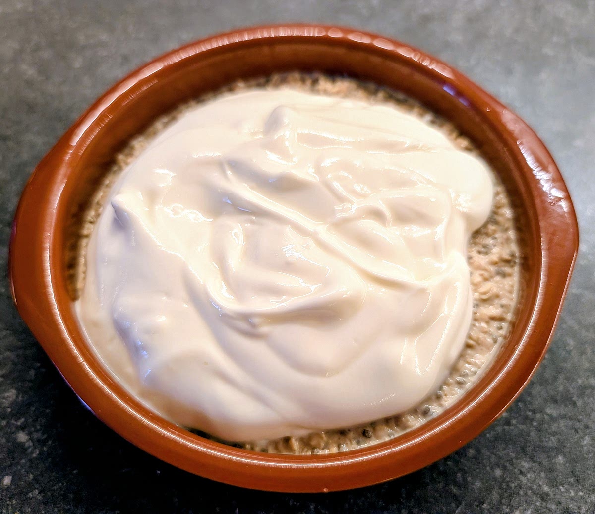 After the cooling period, in a small bowl mix the greek yoghurt with the maple syrup and vanilla extract. Take the oats out of the fridge and pour the flavoured yoghurt over it.