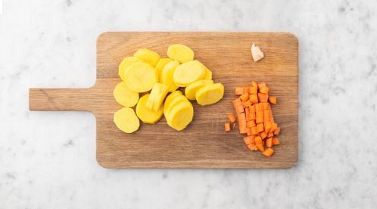 Preheat your oven to 220°C/200
°C fan/gas mark 7. Bring a large saucepan of water with ½ tsp salt to the boil for the potatoes.
Trim the carrot, then quarter lengthways (no need to peel). Cut into pieces about ½cm thick - you want them small, so they cook quickly. Peel and grate the garlic (or use a garlic press). Peel and
slice the potatoes into 1cm thick rounds.