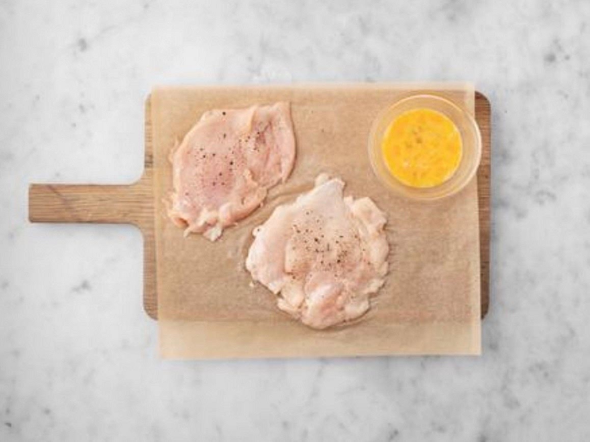 Meanwhile, sandwich each chicken breast between two pieces of baking paper or cling film. TIP: Notice a stronger smell from your chicken? Don’ t worry, this is normal due to packaging we use to keep it fresh. Pop onto a board, then give them a bash with a rolling pin or the bottom of a saucepan until they’re 1-2cm Thick. Season with salt and pepper. Crack the egg (see pantry for amount) into a medium bowl and whisk. Put the breadcrumbs into another large bowl and add the mixed herbs, pepper and salt (see pantry for amount). Mix together.