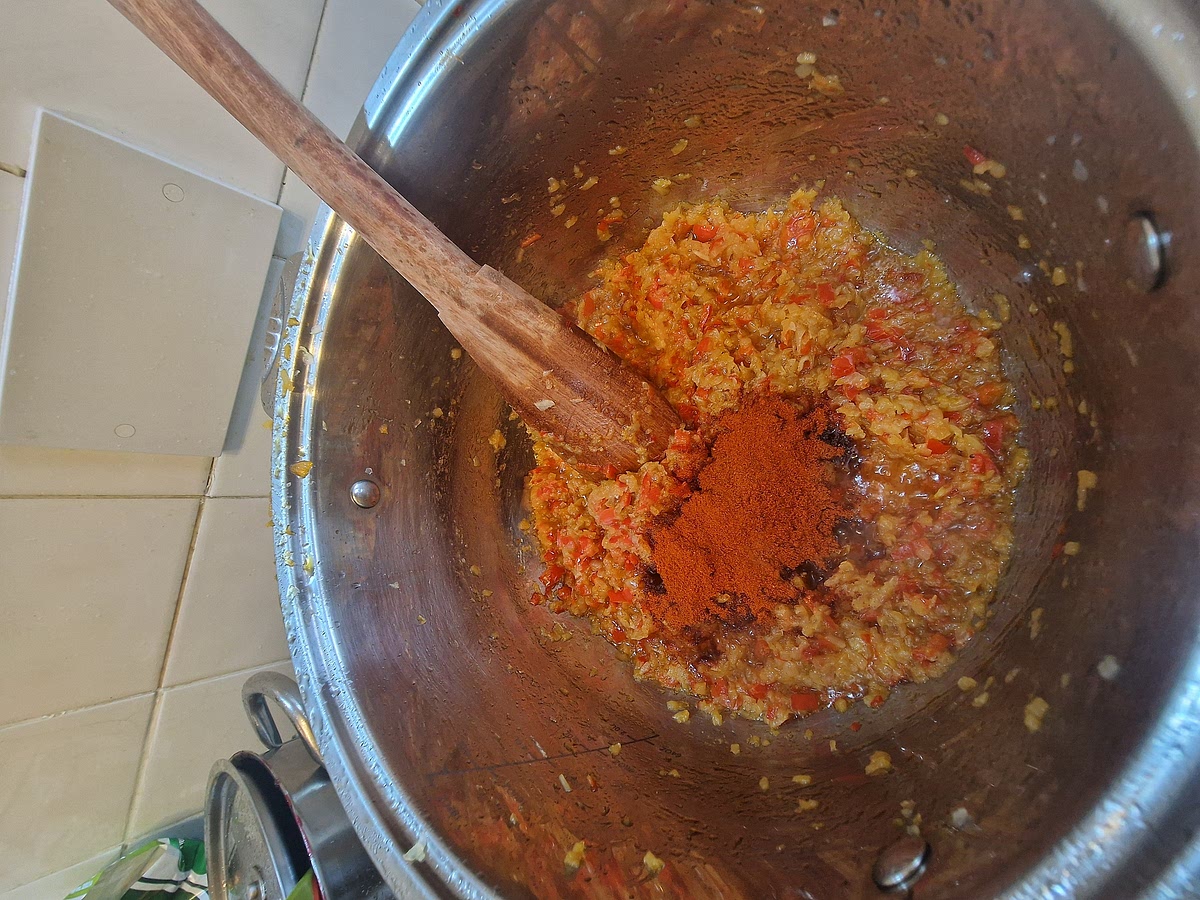 Now you have your base done. Switch off the heat completely and add the paprika powder. I like to add half mild regular paprika powder and half smoked paprika powder. It's not necessary, I just prefer a bit of that smoky flavor. Make sure you don't burn the paprika. The powder burns fast and turns bitter so do it quickly. Stir the powder with the base for about a minute, make sure everything is coated in paprika. There is another optional step, if you want a bit more depth, you can add a spoon of tomato paste now.