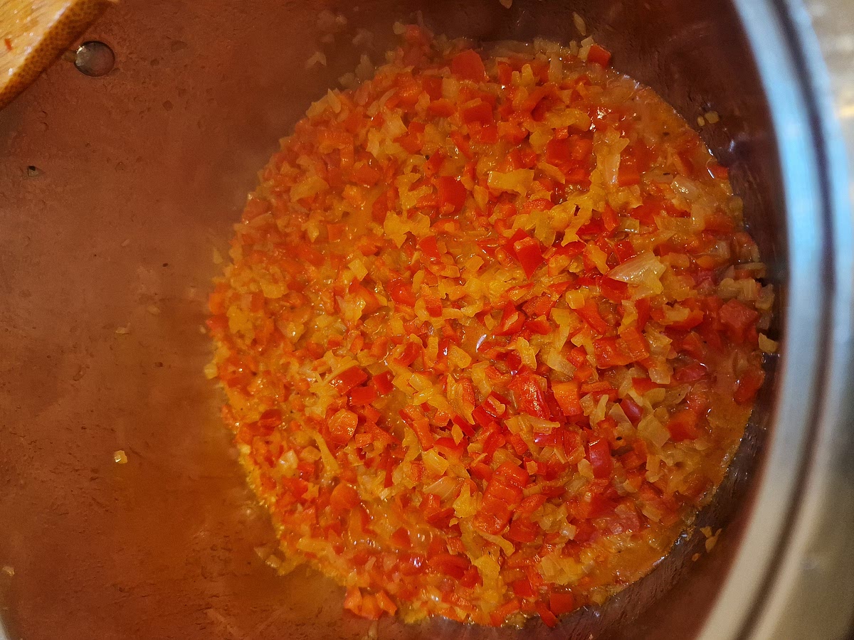 For this step it is important to switch off the heat underneath the pot. Once the onion and peppers are soft and ready, add two heaping spoons of mild paprika powder. Stir everything nicely and once everything is coated in paprika, add a spoon of tomato paste. Stir again.