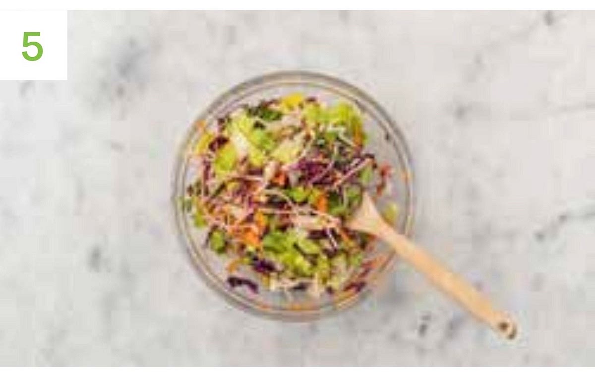 Meanwhile, squeeze the remaining lime juice into another medium bowl and add the sugar and olive oil for the dressing.
Mix together. Add the coleslaw mix and chopped lettuce to the bowl of dressing, then toss to coat. Halve the burger buns, then pop onto a baking tray and into your oven to warm through, 2-3 mins.