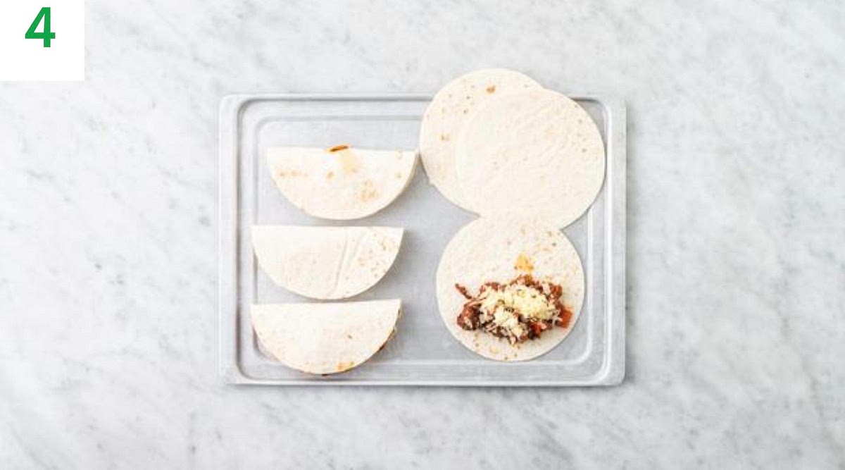 a) Lay the tortillas (3 per person) onto a lightly oiled baking tray. b) Spoon the pork filling onto one half of each tortilla and top with the cheese. c) Fold the other side over to make a semi- circle. Press down to keep together.