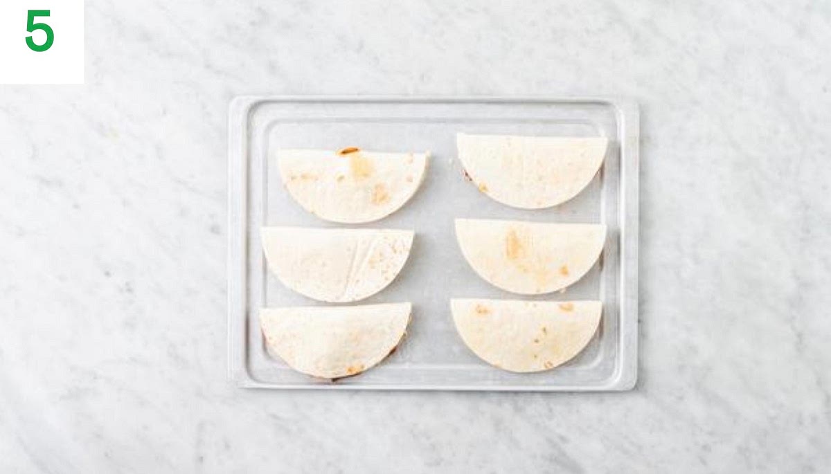 a) Rub each quesadilla with a little oil, then bake on the top shelf of your oven until golden, 4-6 mins. b) Meanwhile, cut the tomato into 1cm chunks. c) In a medium salad bowl, combine the tomato chunks with the sugar and olive oil for the dressing (see pantry for both amounts). Season with salt and pepper and toss to coat.