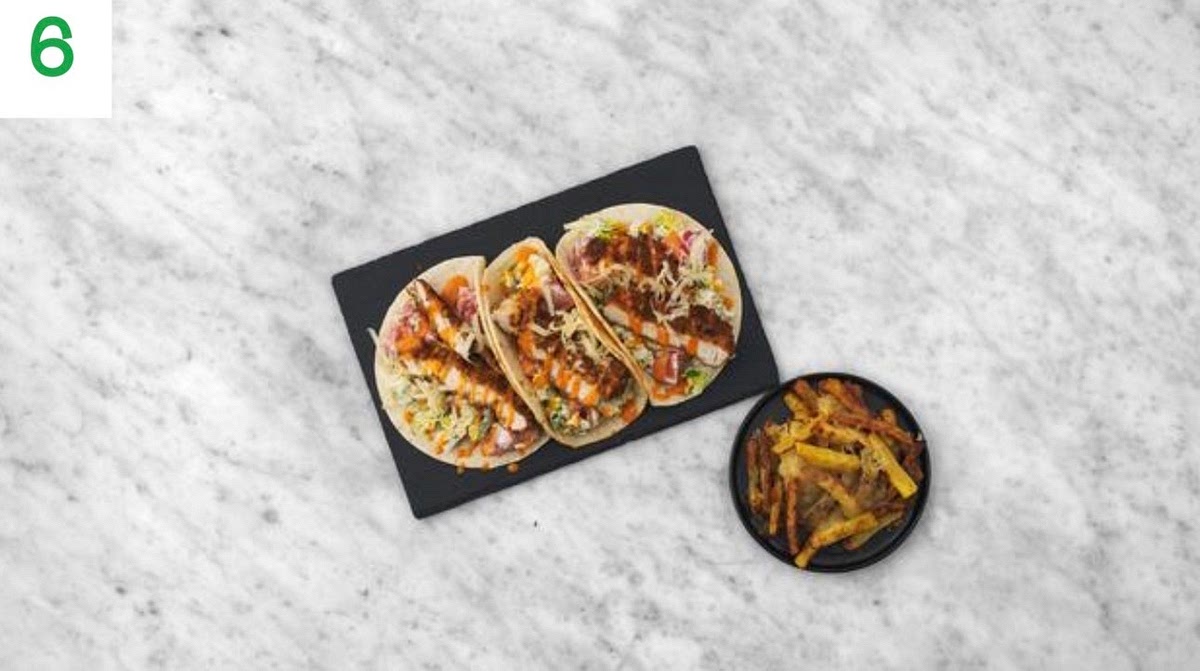 When everything's ready, thinly slice the crispy chicken widthways into 2cm thick slices.
Share the tortillas between your plates. Top with the baby gem and tomatoes, then drizzle over some ranch dressing. Add some crispy chicken slices, a drizzle of buffalo sauce and a sprinkle of the remaining cheese - as much as you'd like.
Serve your tacos and chips with the mayo (see pantry
for amount) and any remaining buffalo sauce for dipping. TIP: Tacos are best enjoyed eaten by hand - get stuck in!