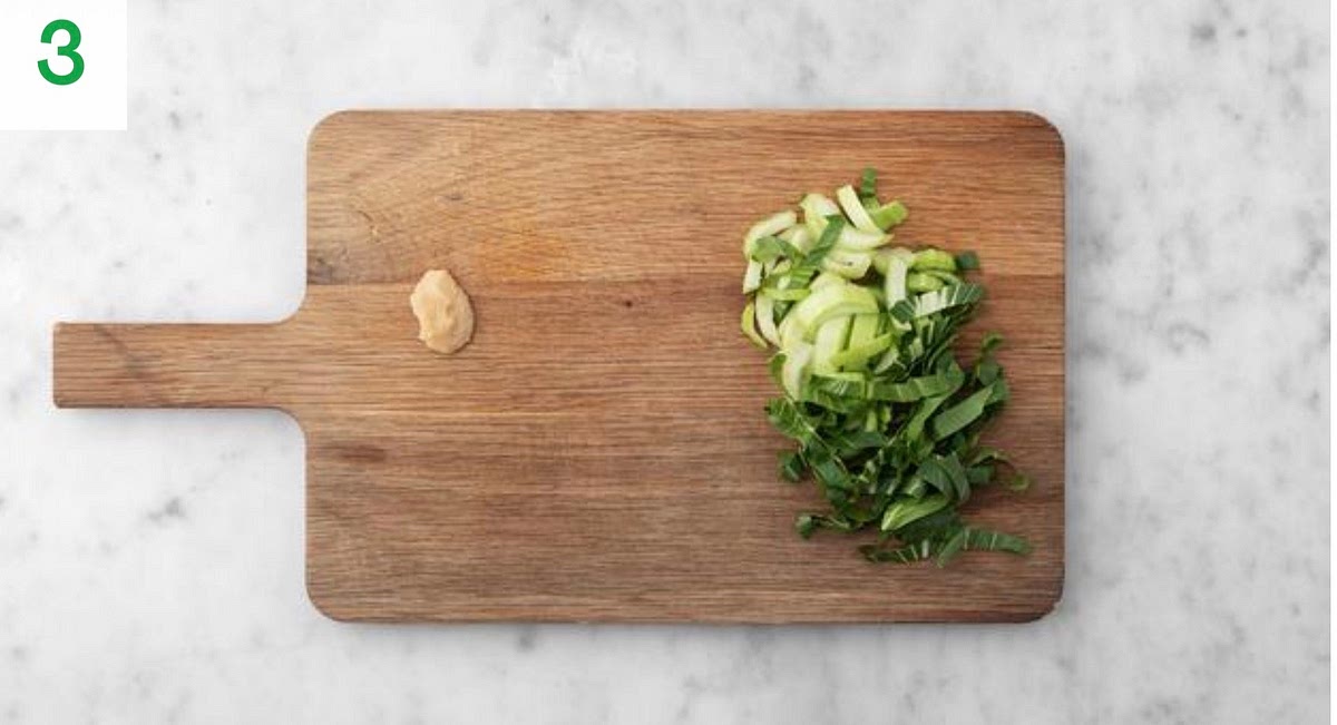 Meanwhile, trim the pak choi, then thinly slice widthways.
Peel and grate the garlic, or use garlic press.