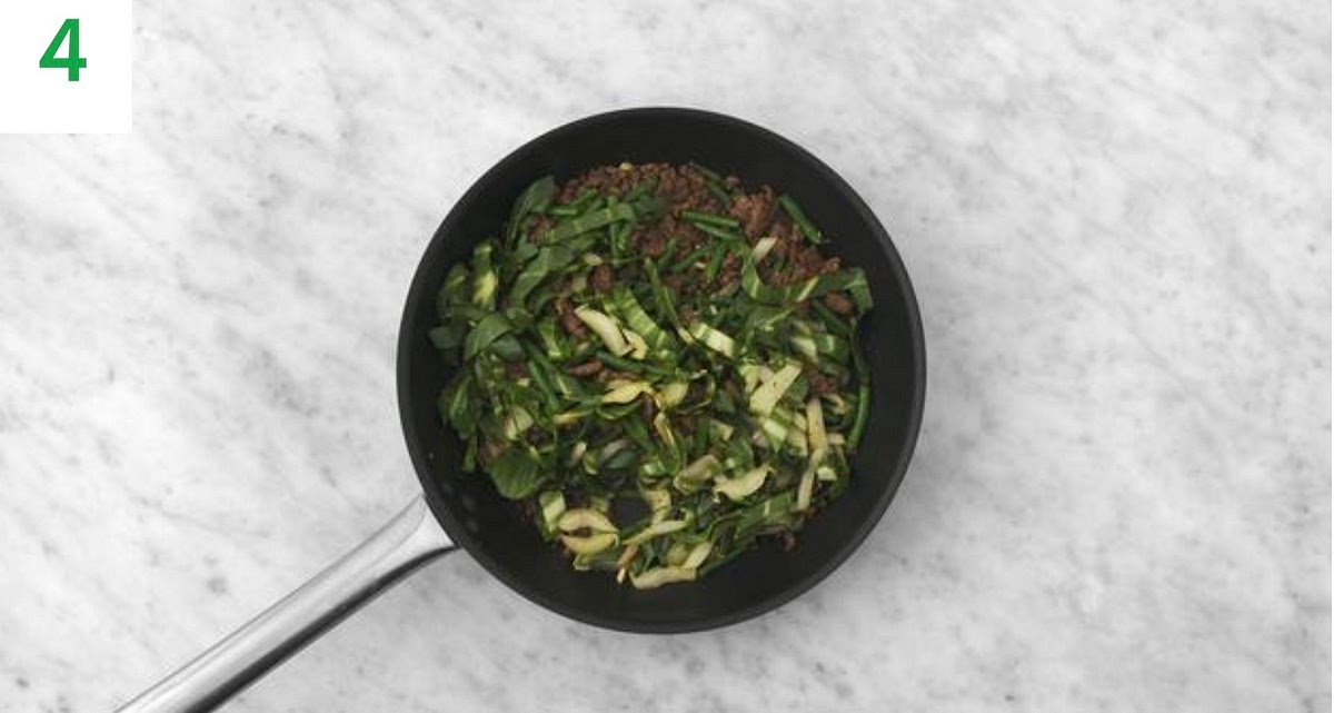 When the mince has browned, drain and discard any excess fat. Season with salt and pepper.
IMPORTANT: The mince is cooked when no longer pink in the middle.
Add the garlic, pak choi and Thai style spice mix (add less if you’d preference things milder) to the pan. Stir-fry, 1 min.