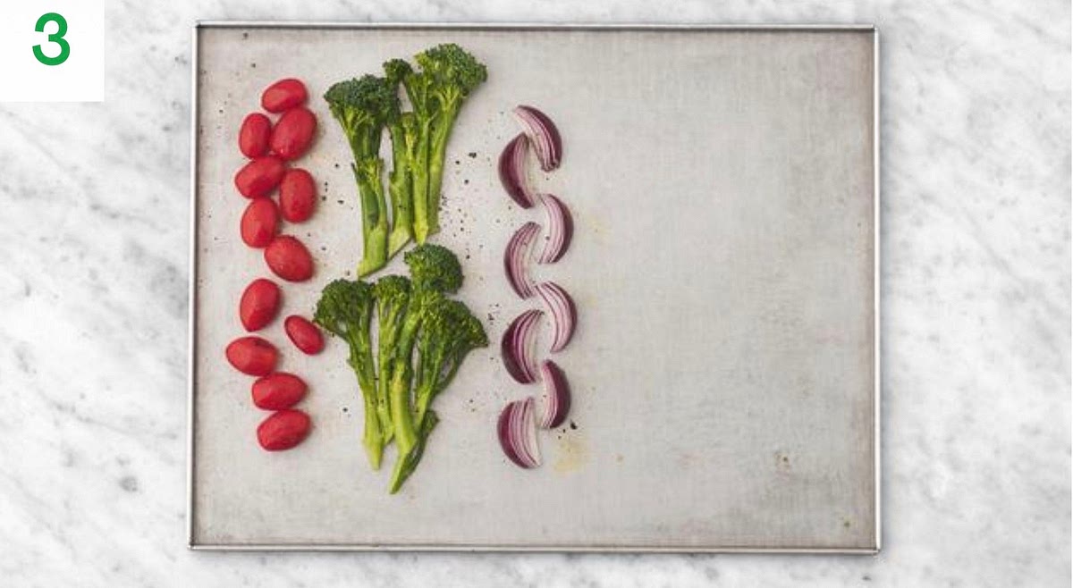 Add the Tenderstem® broccoli, onion wedges and baby plum tomatoes to one side of another large baking tray.
Drizzle with oil, season with salt and pepper and toss to coat.