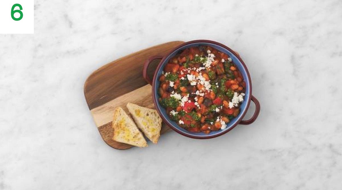 When everything's ready, share the stew between your serving bowls.
Drizzle on the pesto and crumble over the Greek style salad cheese.
Serve the ciabatta triangles alongside for dipping.
